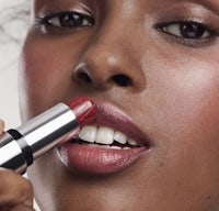 a woman is applying lipstick to her lips